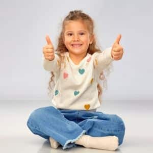 Klein meisje in kleermakerszit met haar duimen omhoog om te laten zien dat de duurzame bankhoezen uit Spanje een eerlijke keuze zijn.