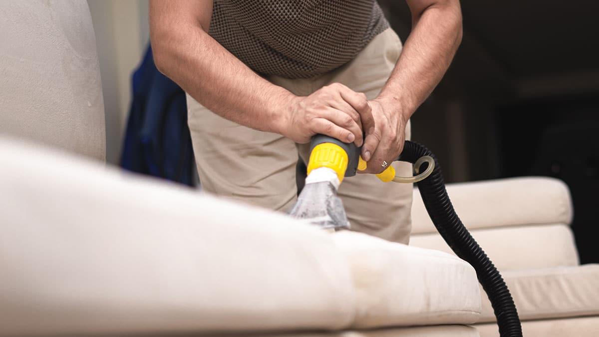 Vakman reinigt een stoffen bank met een professionele extractiemachine