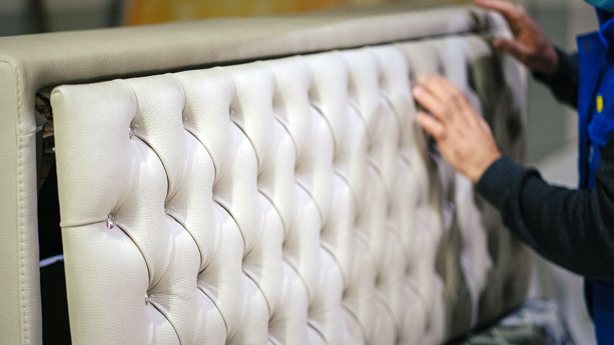 Vakman werkt aan de gecapitonneerde bekleding van een meubel