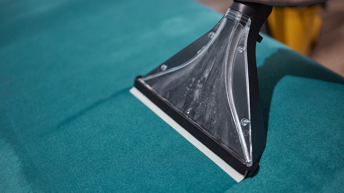 Stoffen meubels reinigen met een professionele extractiemond op turquoise bekleding